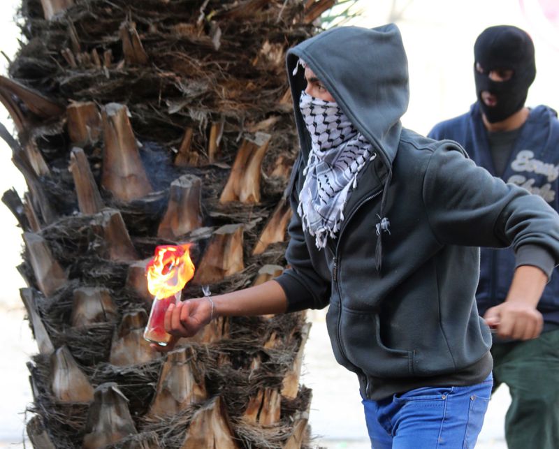 A Palestinian holds a Molotov cocktail in Abu Dis. 