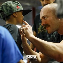 Patrick Cummins applying a fake mustache to a child at UFC on FOX 25 open workouts Thursday at UFC Gym in New Hyde Park, N.Y.