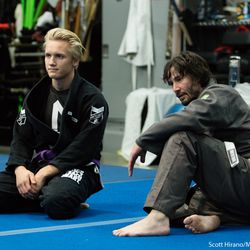 Keanu Reeves watches the instructor explain a technique.