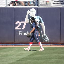 Mandie Perez turns her head towards Jennie Finch’s likeness on the left field wall