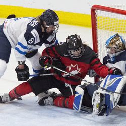 Team Canada forward Meghan Agosta runs into Team Finland goaltender Noora Raty.