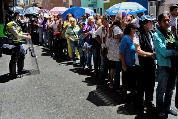 Consumers line up for groceries outside a Caracas supermarket.
