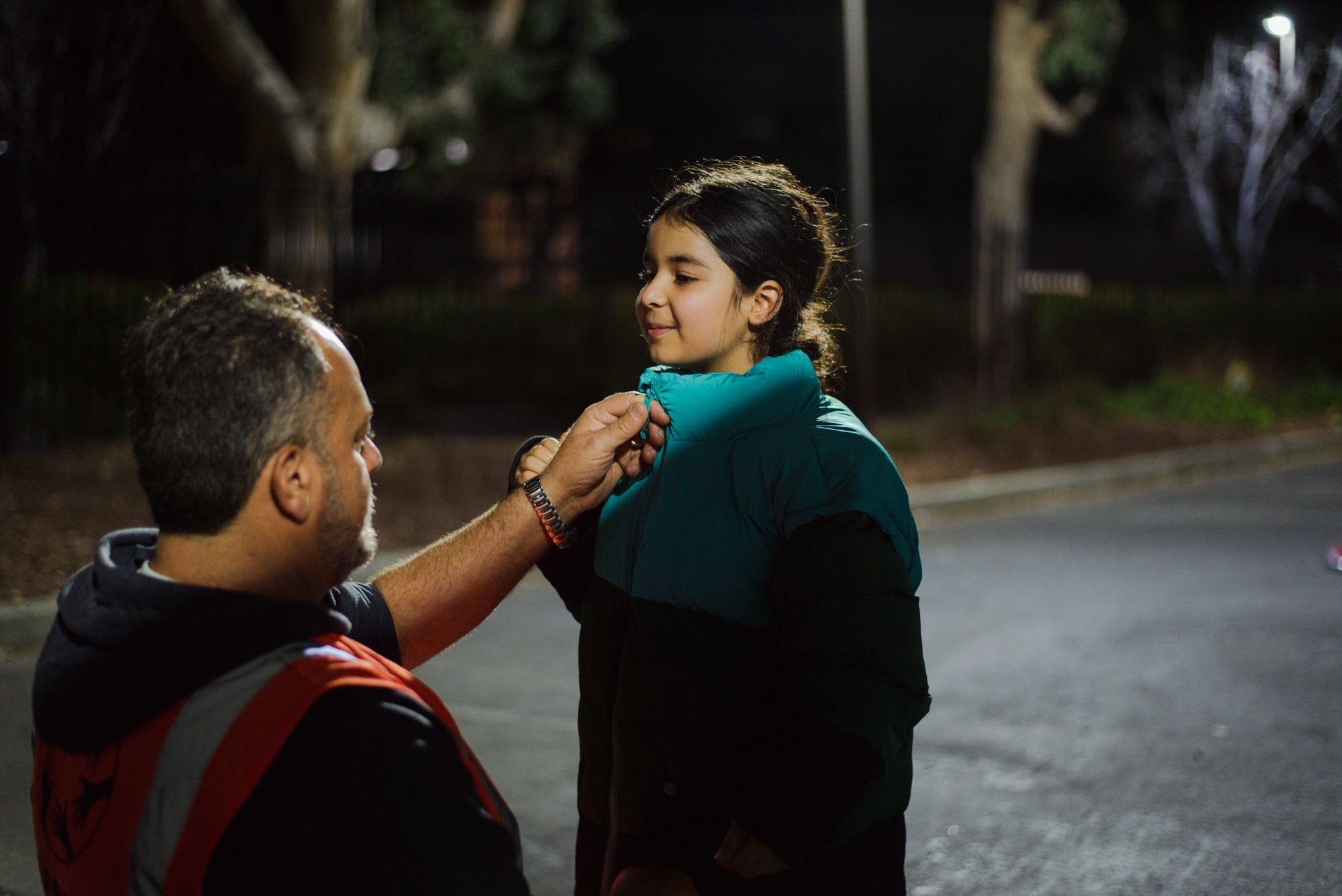 Elbakri zips a new donated coat on Hasenat Wasil, 8, outside the hotel she and her siblings are living at in San Jose.