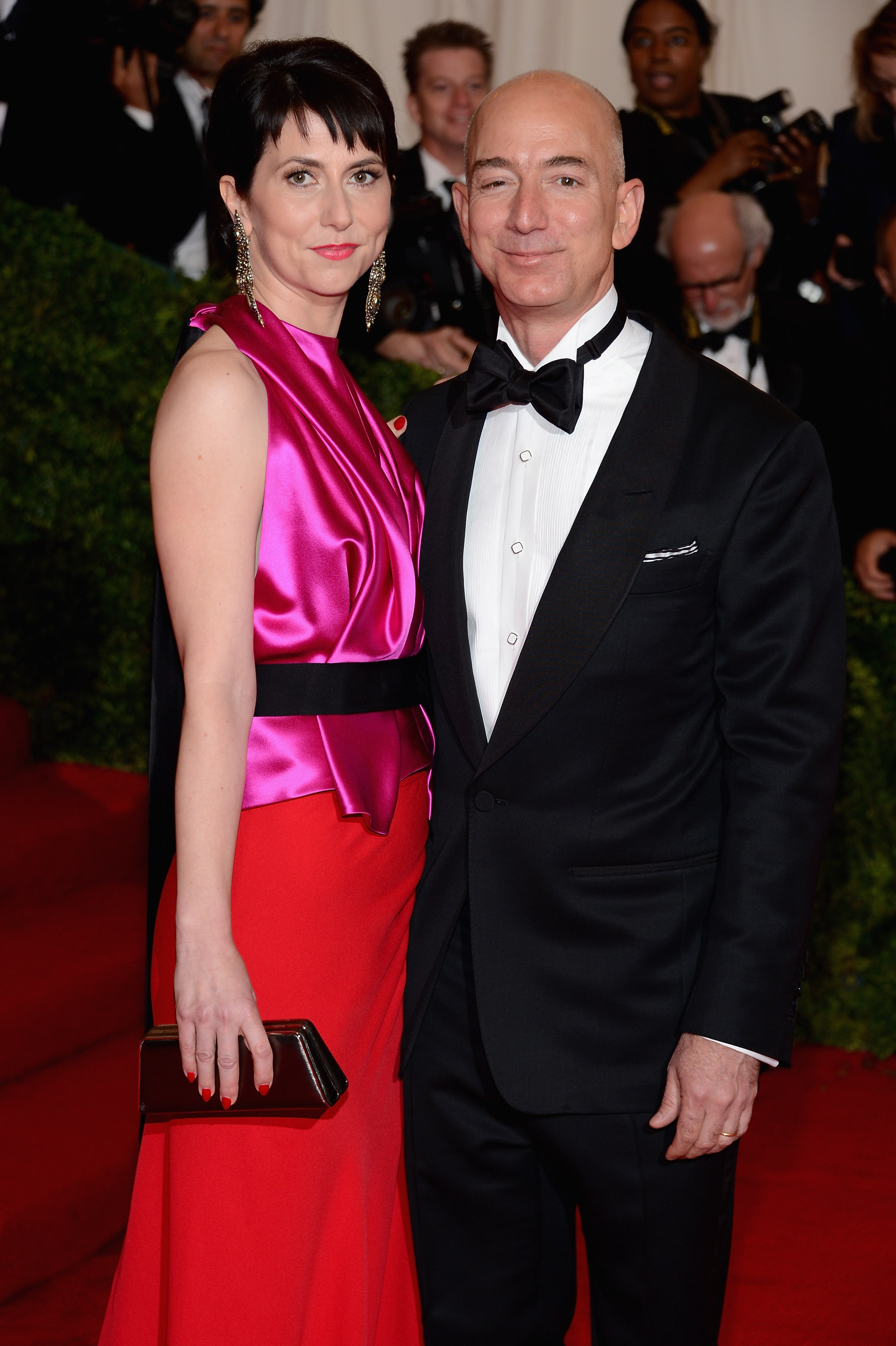 Jeff Bezos in a tux with with his wife MacKenzie in a pink and red gown on red carpet at the 2012 Met Gala in New York City.